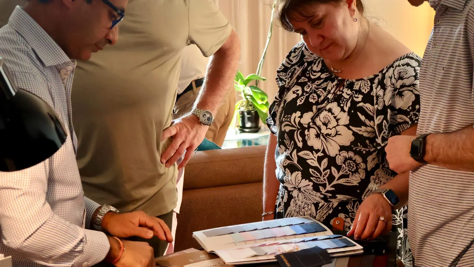 Customers and tailors looking through fabric swatch books together during a consultation